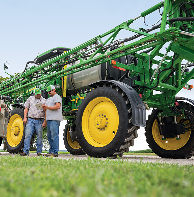 Farmers talking in front of John Deere sprayer